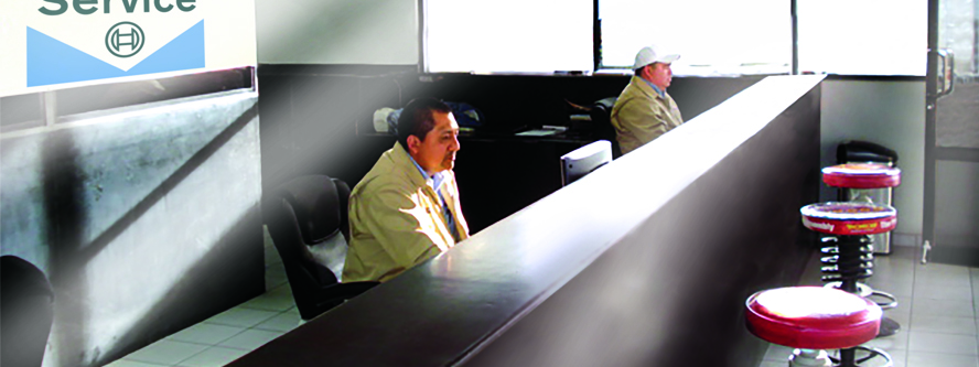 Fotografia de recepcion de mecanica bcs demostrando dos agentes de servicio al cliente trabajando en sus respectivos escritorios.